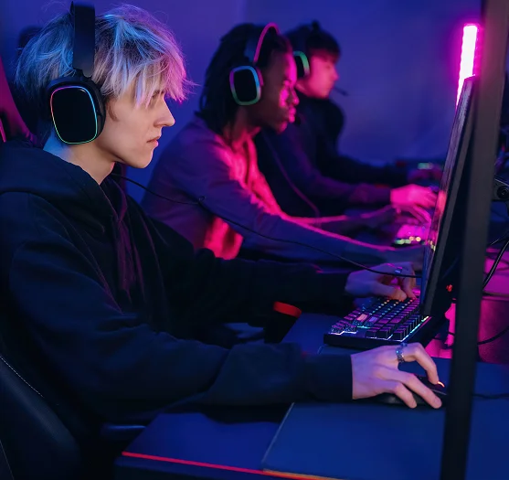 Equipa de jogadores competitivos de PC, equipados com auscultadores RGB para jogos e a jogar em conjunto num centro profissional de eSports com computadores de alto desempenho.
